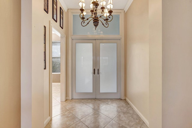 foyer entrance featuring french doors, ornamental molding, an inviting chandelier, and light tile patterned floors