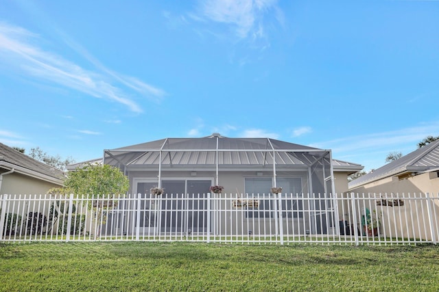 rear view of property featuring a yard and glass enclosure