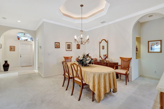 dining room with a notable chandelier, crown molding, light colored carpet, and a raised ceiling