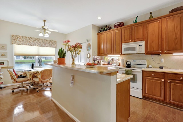 kitchen with tasteful backsplash, white appliances, light hardwood / wood-style floors, and a kitchen island