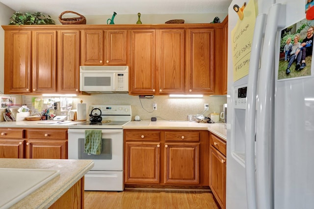 kitchen featuring tasteful backsplash, white appliances, and light hardwood / wood-style floors