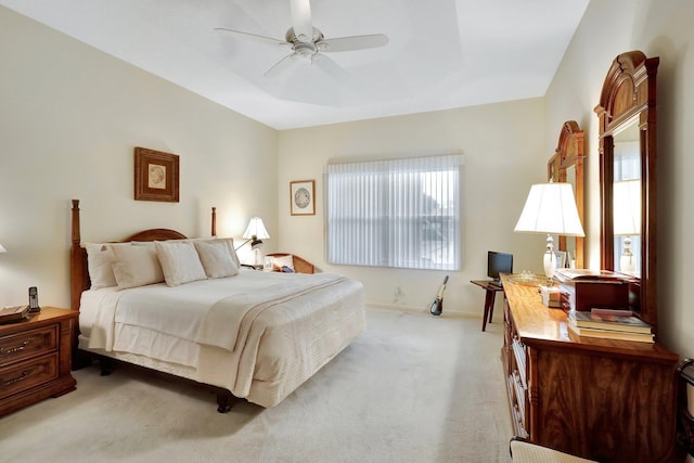 carpeted bedroom featuring a tray ceiling and ceiling fan