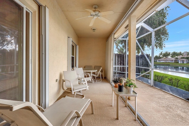 sunroom with a water view and ceiling fan