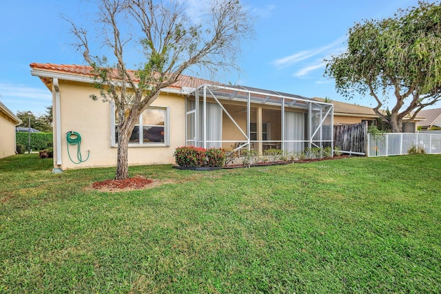 rear view of property featuring a lanai and a lawn