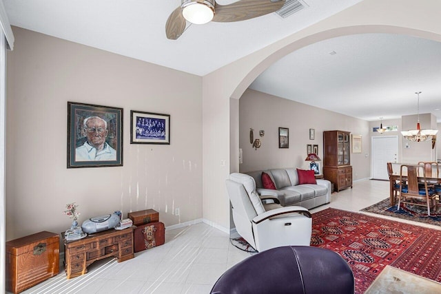 tiled living room featuring ceiling fan with notable chandelier