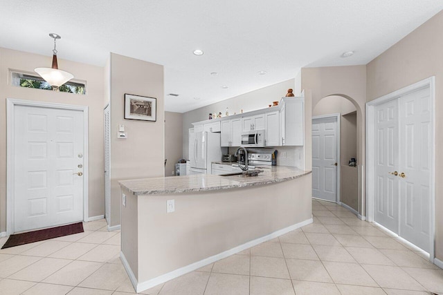 kitchen featuring sink, white appliances, hanging light fixtures, light stone counters, and white cabinets