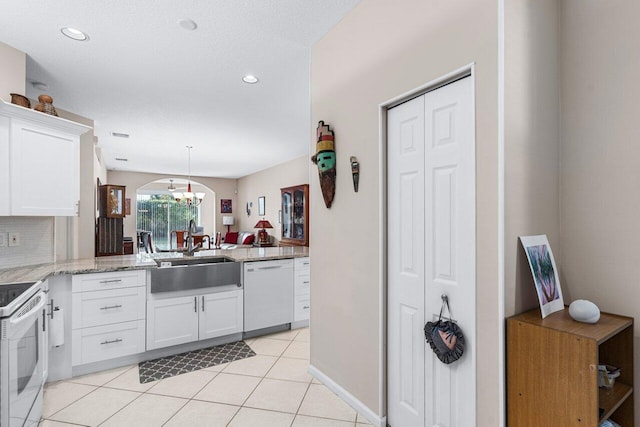 kitchen with sink, white cabinetry, light tile patterned floors, kitchen peninsula, and white appliances