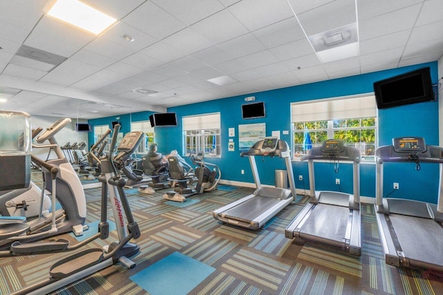 gym with a paneled ceiling and carpet flooring