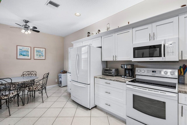 kitchen featuring white cabinetry, light stone counters, light tile patterned floors, white appliances, and decorative backsplash