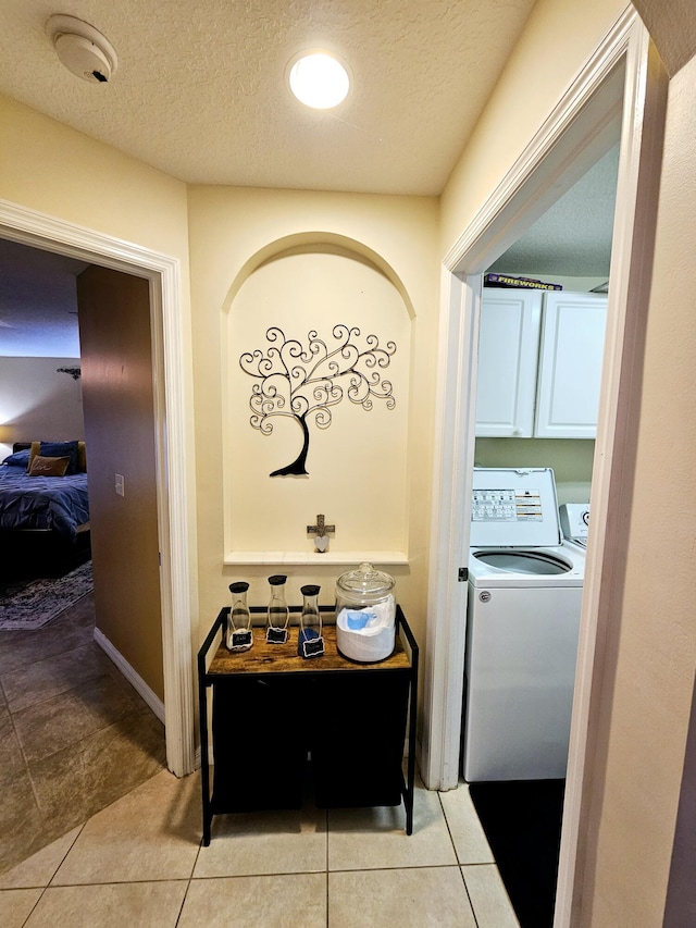 hallway with light tile patterned flooring, a textured ceiling, and washing machine and dryer