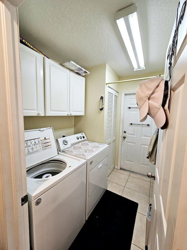 laundry area featuring cabinets, separate washer and dryer, light tile patterned floors, and a textured ceiling