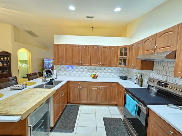 kitchen featuring light tile patterned flooring, sink, stainless steel electric range oven, separate washer and dryer, and beverage cooler