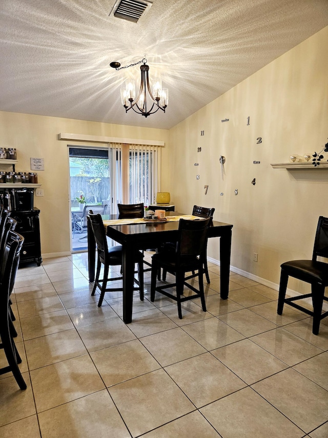 tiled dining space with an inviting chandelier and a textured ceiling