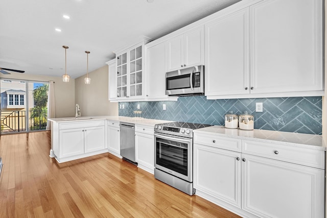 kitchen with white cabinetry, decorative light fixtures, appliances with stainless steel finishes, kitchen peninsula, and backsplash