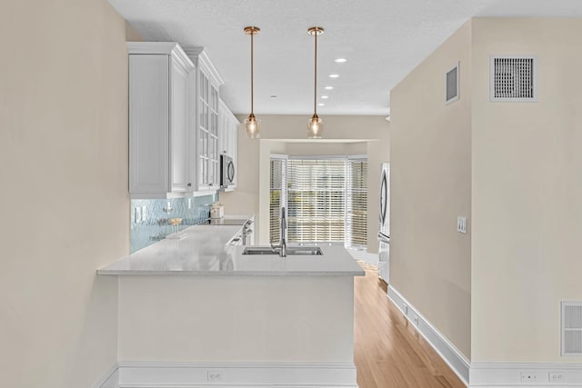 kitchen with sink, pendant lighting, white cabinets, and kitchen peninsula