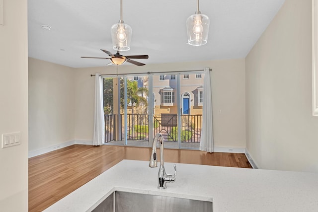 kitchen with ceiling fan, wood-type flooring, decorative light fixtures, and sink