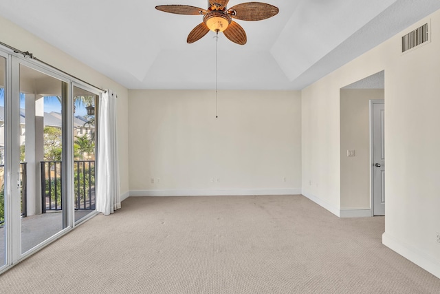 carpeted spare room featuring ceiling fan, lofted ceiling, and a tray ceiling