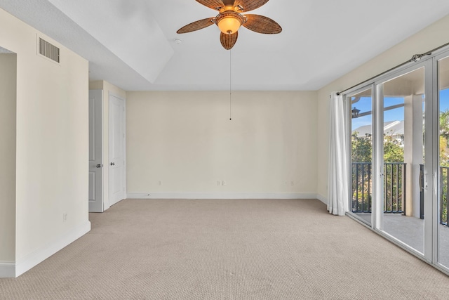 carpeted spare room with ceiling fan and a tray ceiling