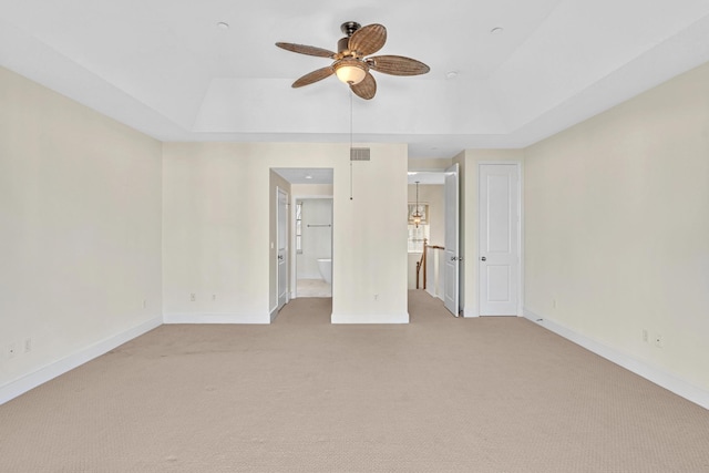 carpeted spare room featuring a raised ceiling and ceiling fan