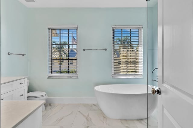 bathroom featuring a tub to relax in, vanity, toilet, and plenty of natural light