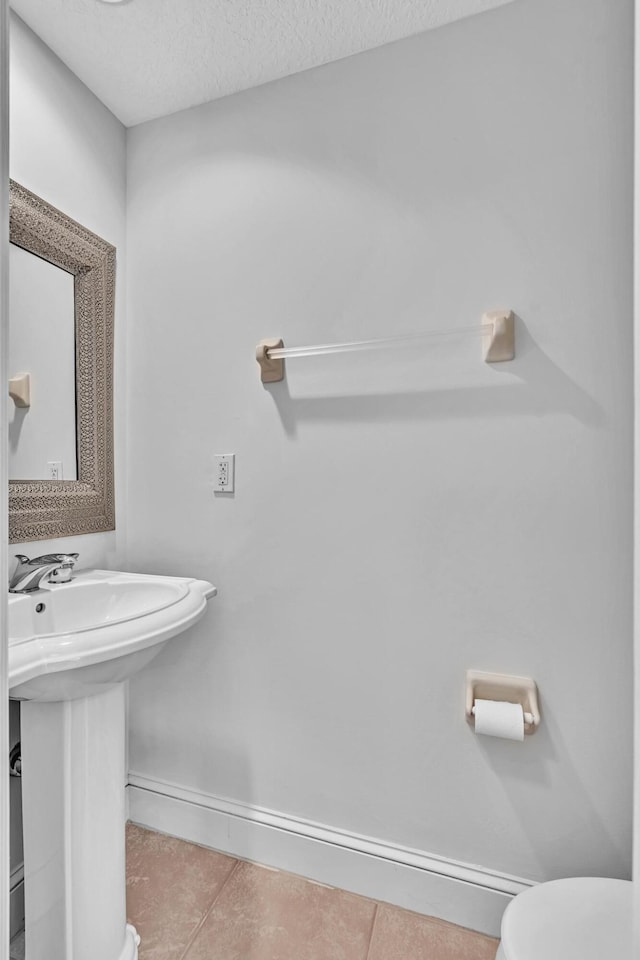 bathroom featuring sink, toilet, tile patterned flooring, and a textured ceiling