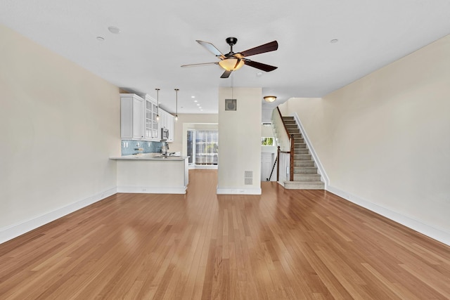 unfurnished living room with ceiling fan and light wood-type flooring