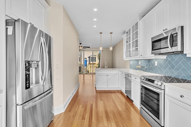 kitchen with pendant lighting, tasteful backsplash, white cabinetry, sink, and stainless steel appliances