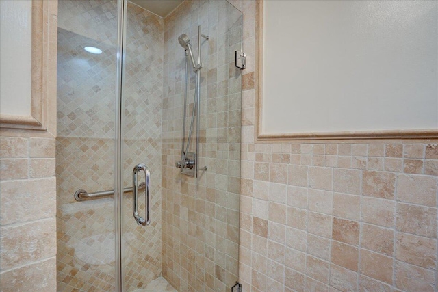 bathroom with tile walls and a shower with door