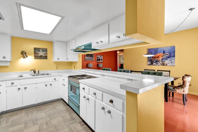 kitchen with stove, sink, kitchen peninsula, and white cabinets