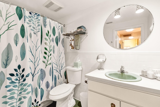 bathroom with walk in shower, vanity, toilet, and tile walls