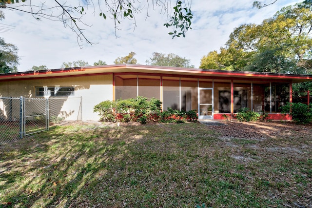 rear view of property featuring a sunroom and a lawn