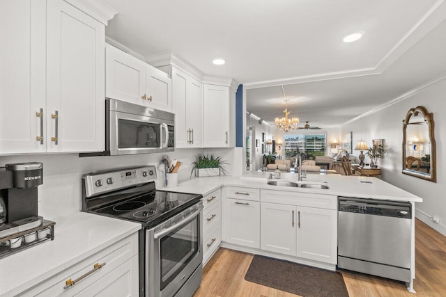 kitchen featuring sink, light hardwood / wood-style flooring, appliances with stainless steel finishes, white cabinetry, and kitchen peninsula