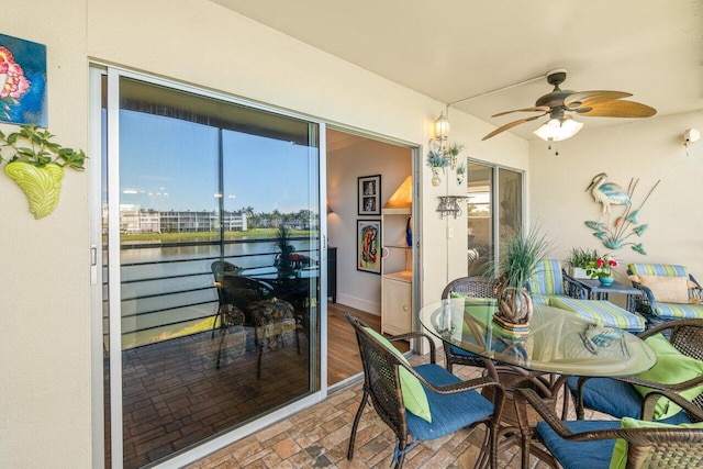 dining room with ceiling fan and a water view