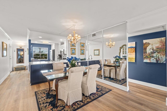 dining area with crown molding, sink, a notable chandelier, and light hardwood / wood-style floors