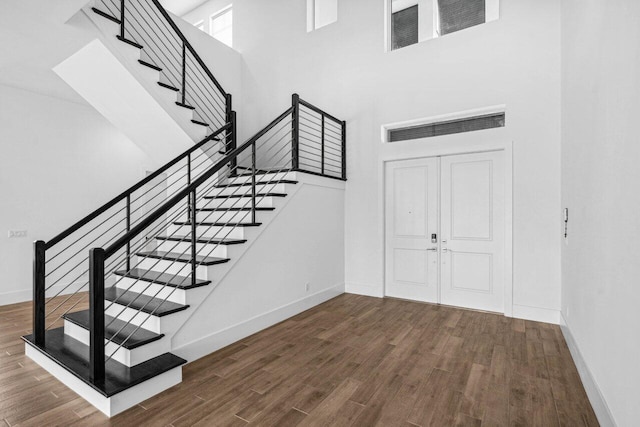 stairway with hardwood / wood-style flooring and a high ceiling