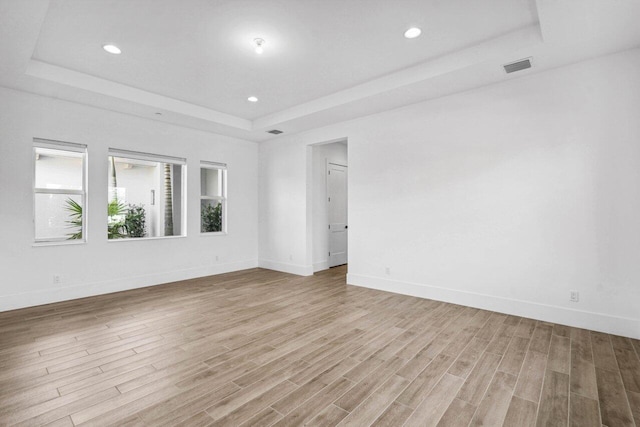 unfurnished room with a raised ceiling and light hardwood / wood-style floors