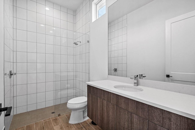 bathroom with tiled shower, vanity, and toilet