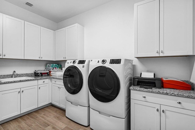 washroom with washer and dryer, sink, cabinets, and light hardwood / wood-style flooring