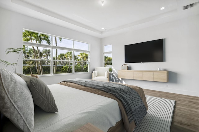 bedroom with a tray ceiling and dark hardwood / wood-style flooring