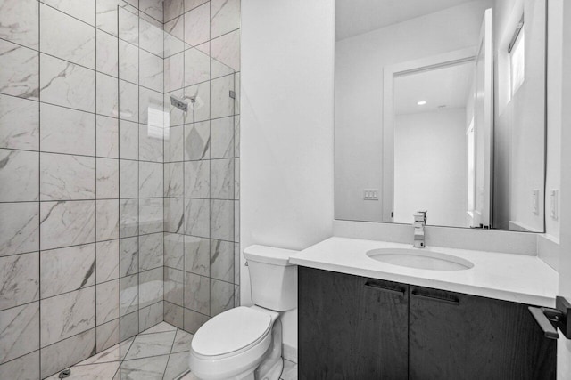 bathroom with vanity, toilet, and tiled shower