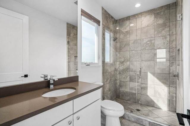 bathroom featuring a shower with door, vanity, and toilet