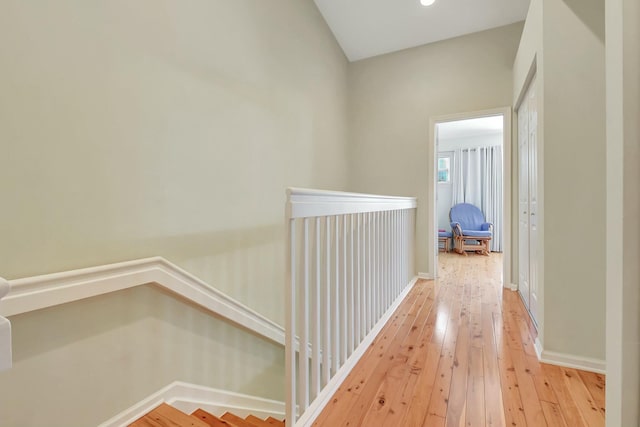 hallway featuring light wood-type flooring, baseboards, and an upstairs landing