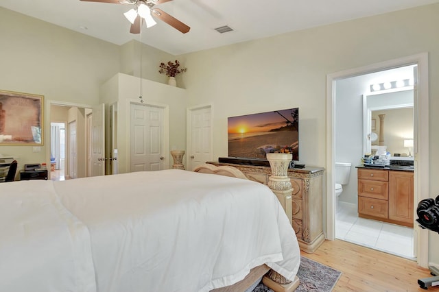 bedroom with ceiling fan, visible vents, light wood-style floors, and ensuite bath