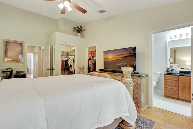 bedroom featuring connected bathroom, a spacious closet, ceiling fan, light hardwood / wood-style floors, and a closet