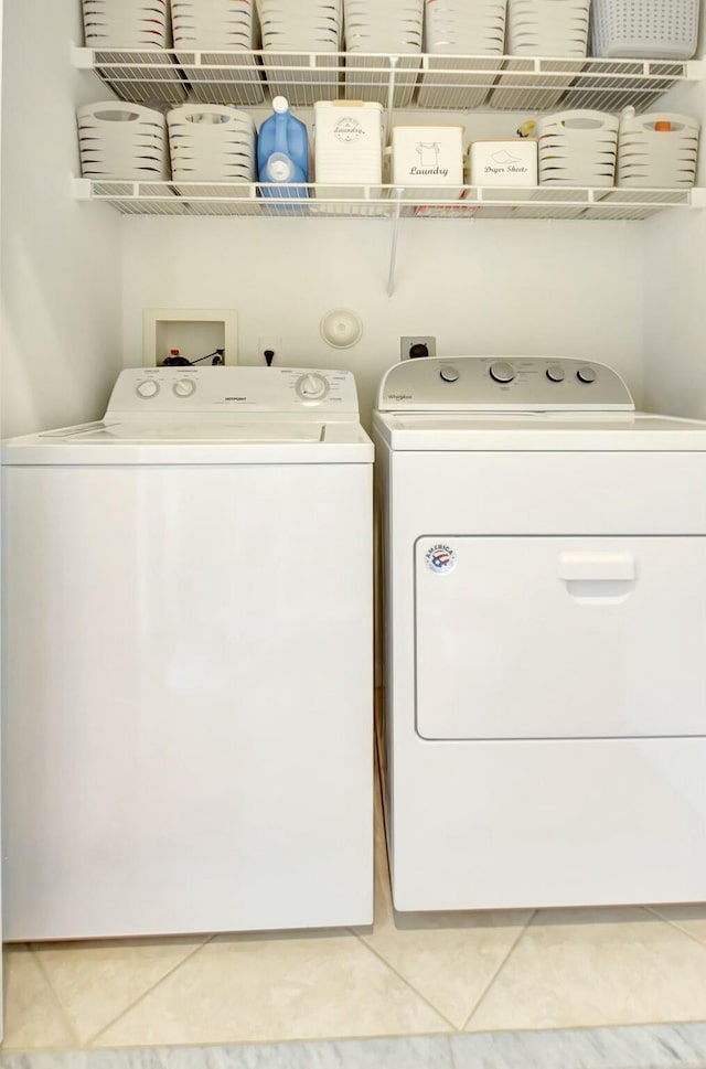 laundry area with washer and clothes dryer and light tile patterned floors