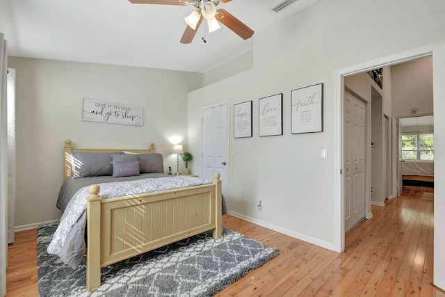 bedroom with visible vents, baseboards, light wood finished floors, and ceiling fan