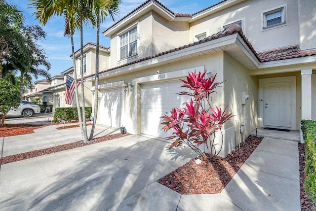 view of front of house featuring stucco siding, a garage, driveway, and a tile roof