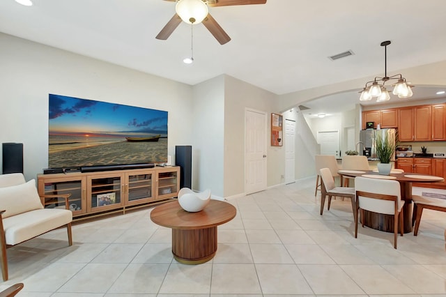 living area with a ceiling fan, light tile patterned floors, baseboards, and arched walkways