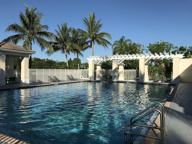 community pool with a patio area, a pergola, and fence