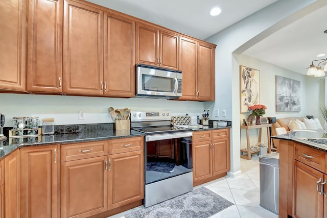 kitchen featuring light tile patterned floors, stainless steel appliances, and dark stone counters